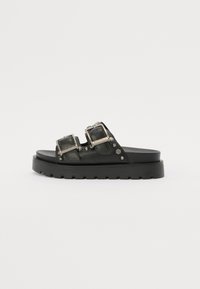Svarte lær-sandaler med to justerbare spenner, nagleprydder og en tykk svart plattformsåle.