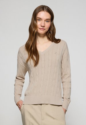 Beige kabelgebreide trui met V-hals en geribde manchetten. Heeft een textuurpatroon en een logoaccent. Lichtgewicht, casual pasvorm.