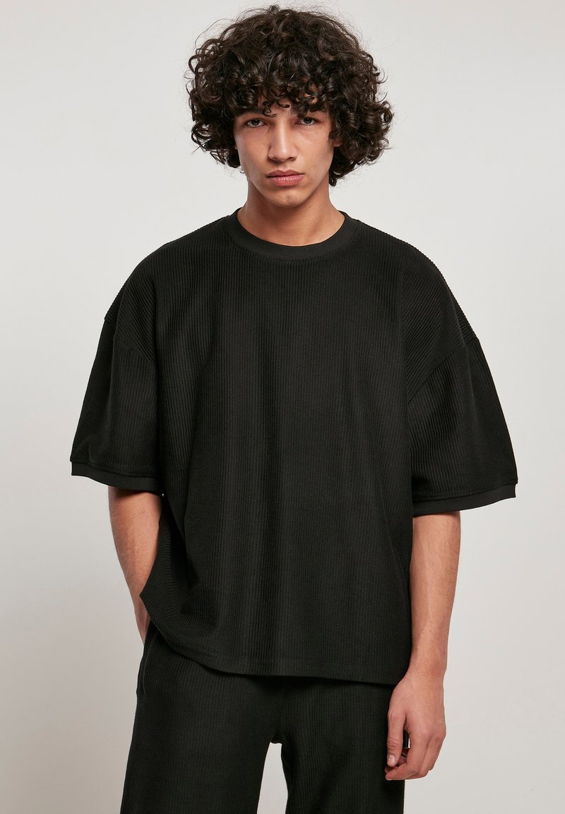 Tricou negru supradimensionat cu mâneci scurte și guler rotund, având un material texturat și o croială lejeră.