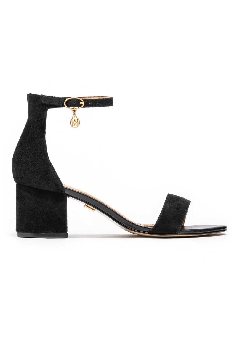 Must musta bloki kontsa sandaalid ankle strap'iga, kuldse detailiga, avatud varvasega ja lamedal tallal. Omab minimalistlikku disaini ja siledat tekstuuri.