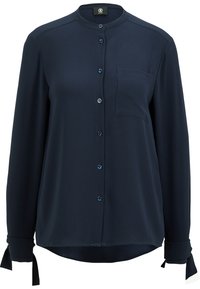 Mörkblå långärmad blus i slätt tyg, med krage, knäppning framtill och en ficka på vänster sida. Knyts vid ärmsluten.