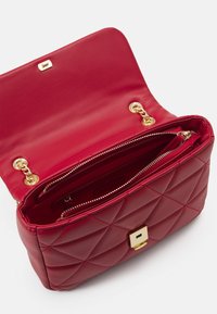 Borsa a tracolla in pelle trapuntata rossa con un clasp dorato, dettagli in catena e una tasca con zip all'interno. Texture liscia con una forma strutturata.