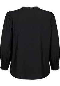 Blouse noire à manches longues, texture douce, poignets smockés et détail d'encolure festonnée, avec une coupe ample et décontractée.