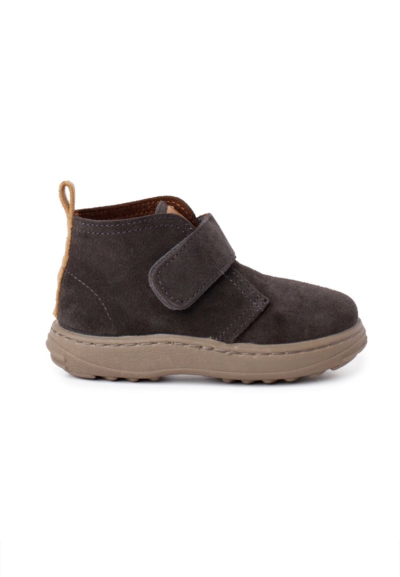 Stivaletto alla caviglia in suede grigio scuro con nastro in velcro, tallone posteriore texturizzato color beige e suola in gomma flessibile con pattern antiscivolo.