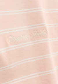 Tissu rose clair avec fines rayures horizontales blanches et texte brodé subtil « Originals Structure » en cursive.