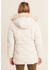 Giacca invernale imbottita di colore beige chiaro con cappuccio foderato in pelliccia. Presenta un motivo a rombi e maniche lunghe, progettata per calore e copertura.