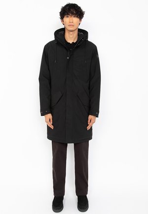 Parka negra con capucha, con cierre de botones en la parte delantera, dos bolsillos frontales y puños elásticos. El material parece suave y duradero, con un ajuste casual.