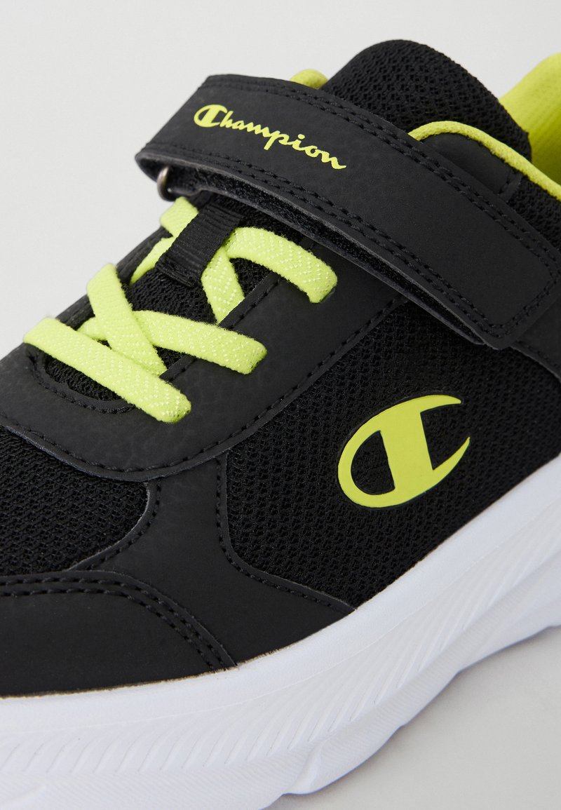 Czarne buty sportowe z siateczką i materiałem syntetycznym, neonowo-żółte sznurowadła oraz rzep. Biała gumowa podeszwa z detalem logo.
