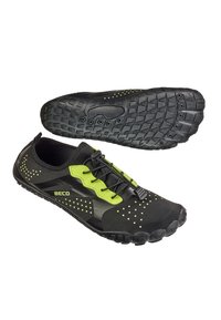 Baskets de sport noires avec accents verts, semelle en caoutchouc texturé et mécanisme de laçage. Présente un design perforé pour une meilleure respirabilité.