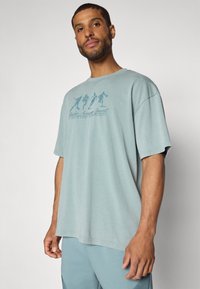 Under Armour ATHLETES  - Apdrukāts T-krekls - serpentine/jasper blue