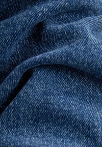 Tmavomodrý denímový úplet s jemnou texturou, s diagonálními tkaninovými vzory a měkkým, mírně broušeným povrchem.