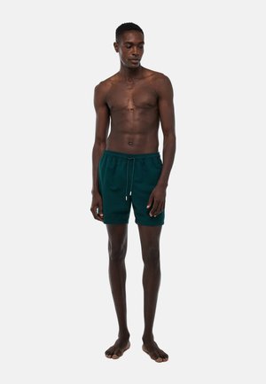 Shorts de bain texturés verts avec une taille élastique et un cordon de serrage, dotés de poches latérales et d'une coupe décontractée.
