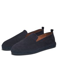 Zapatos de ante azul marino tipo slip-on con suela plana de yute trenzado y una parte superior suave y texturizada. Cuenta con un perfil bajo y acentos laterales elásticos.