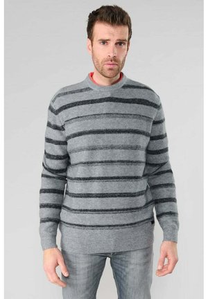 Gray sweater with horizontal black stripes, crew neck, ribbed cuffs and hem, soft texture, worn over a red shirt.