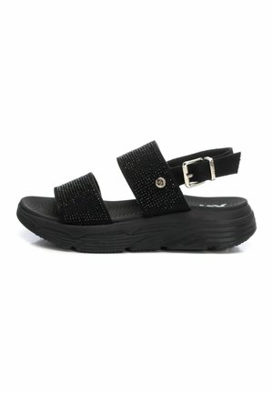 Sandalias negras con dos correas anchas, adornadas con piedras brillantes. Presenta una suela texturizada y una correa de tobillo ajustable con hebilla metálica.
