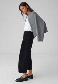 Gray wool blend jacket, white shirt, black corduroy trousers, and black leather loafers. The jacket features a cropped design with wide sleeves.
