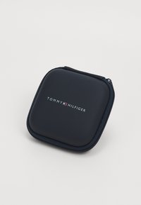 Tommy Hilfiger juodas užtrauktuku uždaromas dėklas, kvadrato formos, lygus paviršius, priekyje yra baltas ir raudonas logotipas, su tvirtu užtrauktuku.