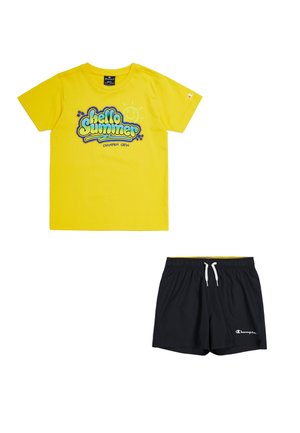 T-shirt di cotone gialla con grafica "Hello Summer", abbinata a pantaloni da bagno neri con vita elasticizzata e cordino bianco.
