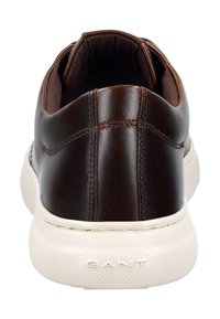 Hnědé kožené tenisky s texturovaným povrchem, bílé gumové podrážky a kontrastním šitím. Zadní pohled ukazuje měkký límec a logo značky.