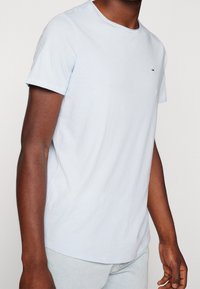 Světle modré bavlněné tričko má kulatý výstřih a krátké rukávy. Na hrudi je malé logo, má hladkou strukturu a slim fit střih.