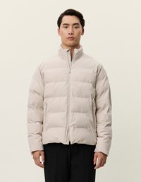 Casaco puffer bege com gola alta, design quilted horizontal, fecho de zíper e dois bolsos frontais, feito de material leve e suave.