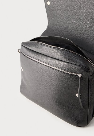 Črna teksturirana usnjena torba z sprednjim žepom z zadrgo in odprto glavno pregrado, ki je zavarovana s poklopcem s pritisnimi gumbi.