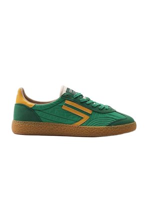 Scarpa da ginnastica bassa verde e gialla con suola marrone strutturata, striscia laterale a zigzag e lacci verdi, mostrata di profilo destro su sfondo bianco.