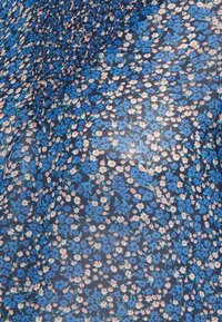 Tyg med tät blommönster som har små blå, vita och orange blommor på en mörk bakgrund, samlat upptill.