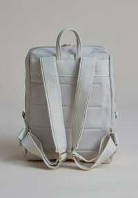 Grå tygryggsäck med vadderad struktur, justerbara remmar, dragkedjestängning och handtag på toppen. Har guldfärgad hårdvara och texturerade detaljer.