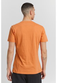 Narancssárga pamut póló vékony szabással, rövid ujjú és kerek nyakkivágással. Simaszövetes, egyszínű dizájn, és egy kis címke a szegélyénél.