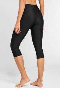 Black capri leggings made of stretchy fabric, featuring a fitted design and a smooth texture; hits just below the knee.