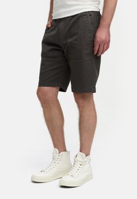 Bermudas de algodón gris oscuro con cintura elástica, bolsillos laterales y corte recto, combinadas con zapatillas altas blancas.