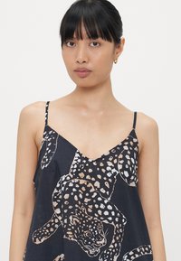 Ujjatlan, tengerészkék ruha V-kivágással, bézs és fehér leopárdmintával. Könnyű anyag és állítható vékony pántok.