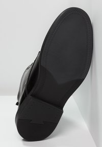 Černá kožená bota s hladkou podešví a texturovaným vzorem, se zkoseným designem podpatku a detailním prošíváním podél okrajů.