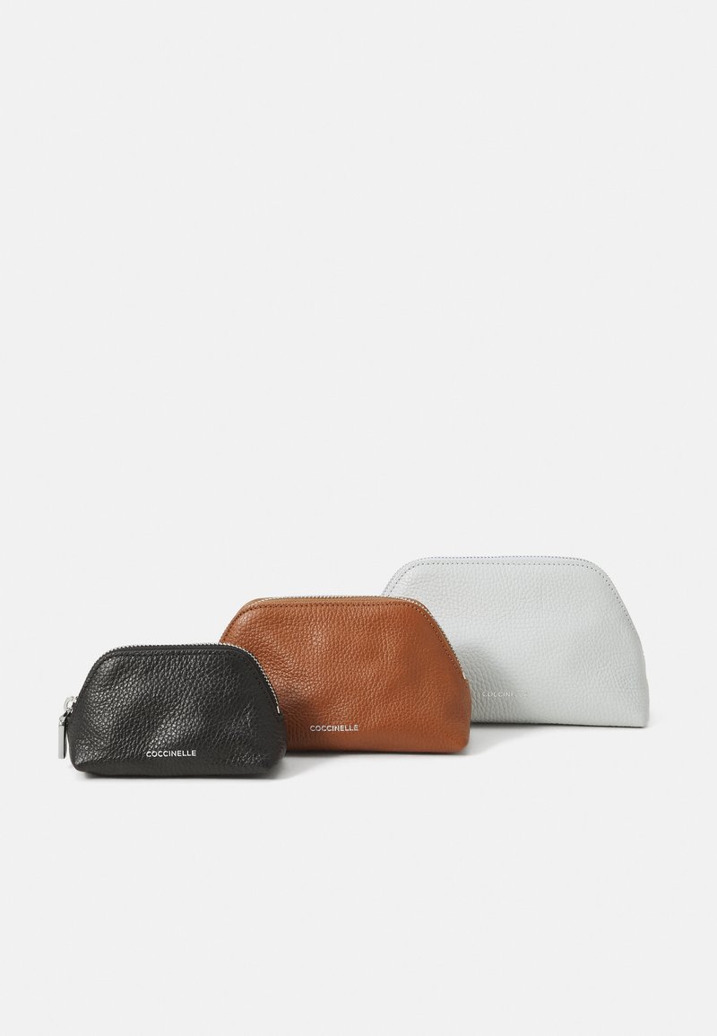 Three zippered leather pouches in black, brown, and light gray, featuring a textured finish and a rounded shape, with subtle branding on the front.
