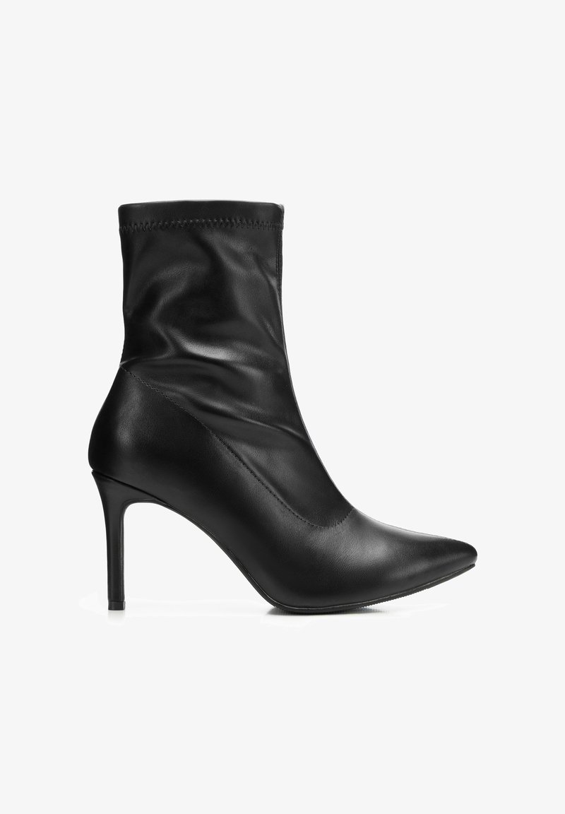 Botín negro de cuero con punta afilada y tacón de aguja delgado, parte superior suave arrugada, vista lateral sobre fondo blanco.