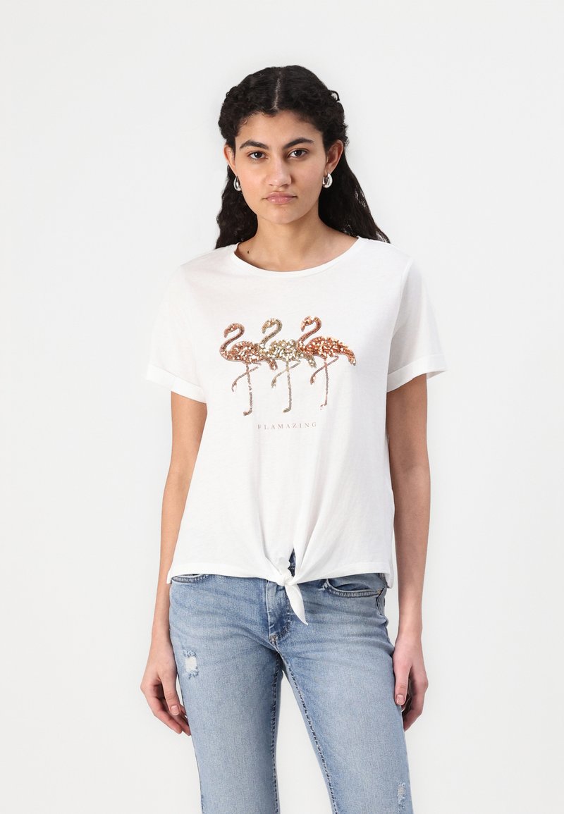 Hvid bomulds t-shirt med en bundet frontknude, udsmykket med tre pailette-flamingoer i kobber, guld og rosaguld over teksten "FLAMAZING."
