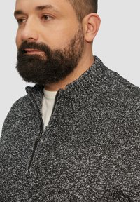 Pullover mit Viertelreißverschluss aus strukturiertem schwarz-weißen Strick, mit Stehkragen und Reißverschluss. Weicher Stoff, lässige Passform.