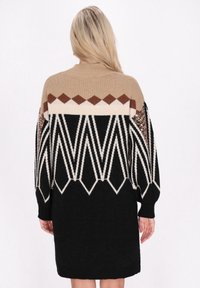 Abito maglione oversize con motivi geometrici in beige, marrone e nero. Caratterizzato da maniche lunghe e un tessuto testurizzato con accenti luccicanti.