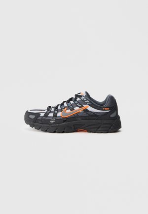 Sort og grå Nike P-6000 sneaker med orange Swoosh-logo og accenter, mesh-overdel og tekstureret sål vist i sideprofil på hvid baggrund.