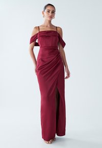 Burgunderfarbiges Abendkleid mit schulterfreien Ärmeln, taillierter Oberteil, drapierten Details und einem Oberschenkelspalt; aus glattem Satinmaterial gefertigt.