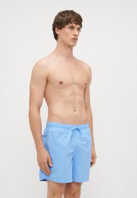 Jasnoniebieskie szorty kąpielowe wykonane z miękkiego materiału, z elastycznym pasem w talii ze sznurkiem oraz bocznymi kieszeniami, zaprojektowane z myślą o wygodzie.