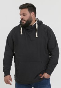 Svart hettegenser laget av mykt stoff, med kengurulommer, kontrastfargede snorer og en liten logopatch nær kanten.