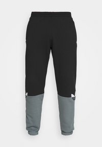 Svarta och grå joggingbyxor med resår i midjan, mudd i bensluten och tre ränder på sidan. Gjorda av mjukt, strukturerat tyg.