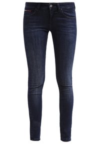 Jeans ajustados de mezclilla azul oscuro, con una cintura de altura media, diseño de cinco bolsillos y un leve desvanecimiento a lo largo de las piernas. Costuras clásicas visibles.