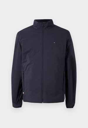 Marinefarbene, leichte Jacke mit Stehkragen, durchgehendem Reißverschluss, zwei Seitentaschen und einem kleinen Logodetail auf der oberen linken Brust.