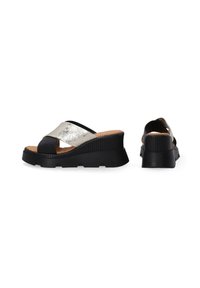 Zwarte en zilveren sandalen met kruislings over elkaar lopende banden, een gestructureerde wigzool en een kurken binnenzool. Glad metallic en matte afwerkingen.