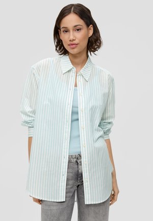Camisa de botones de rayas en azul claro y blanco, con cuello, mangas largas y un corte relajado, sobre una blusa sin mangas a juego.