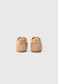 Sneaker in suede beige con profilo basso, caratterizzate da dettagli perforati, punta rotonda e morbida fodera in tessuto. Suola in gomma per una migliore aderenza.