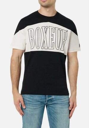 Mann trägt schwarz-weißes Color-Block-T-Shirt mit großem "BOXEUR" Schriftzug auf der Brust und hellblaue Jeans.